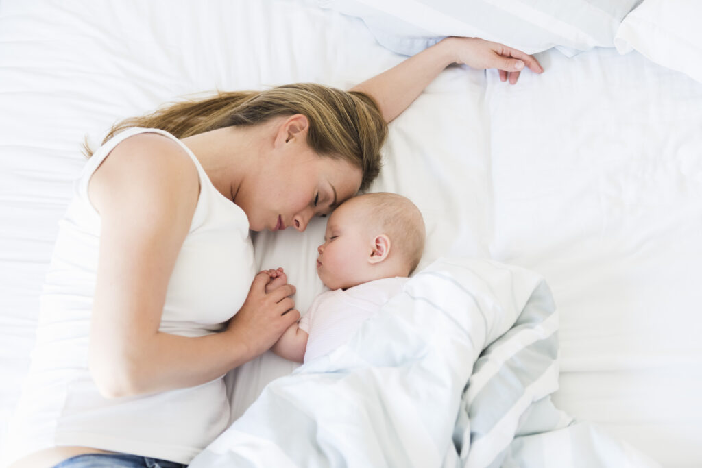 Schlafberatung online - Baby im Bett mit Mama halten Hand
